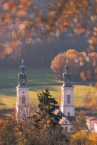 Tower amidst trees and buildings against sky