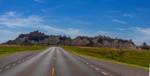 Road amidst field against sky