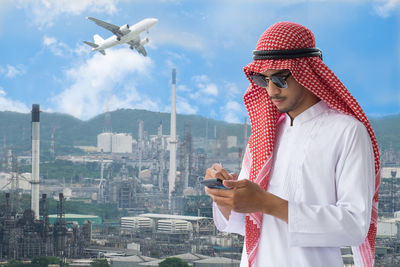 Low angle view of man using mobile phone against cityscape