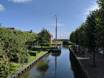 Canal amidst trees and buildings against sky