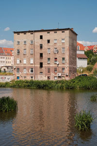 Buildings by lake against sky