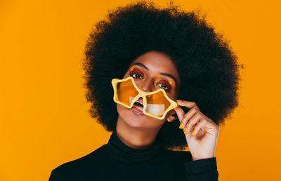 Portrait of smiling young woman holding yellow camera