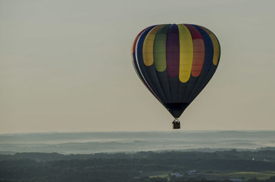 Colorful hot air balloon over landscape against sky