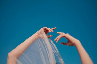 Low angle view of hand against blue background
