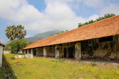 Houses on field by building against sky