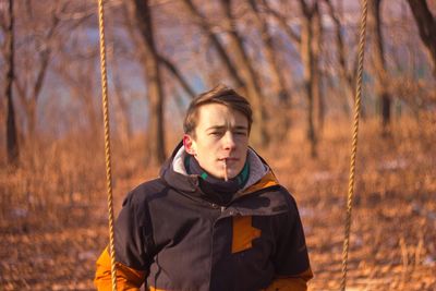 Portrait of young man smoking cigarette against trees