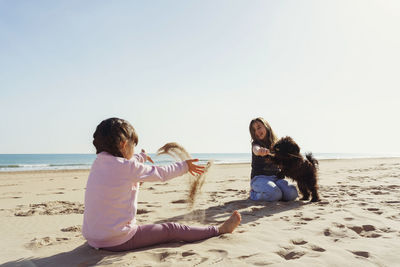 Two sisters playing with dog at beach