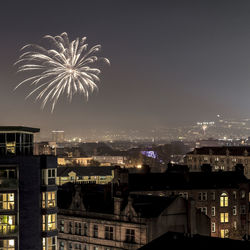Firework display over city against sky at night