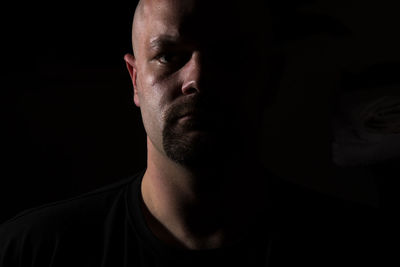 Close-up portrait of man against black background