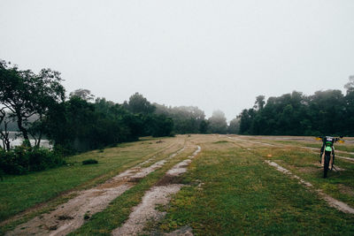 Road amidst field against clear sky