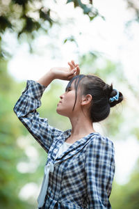 Young woman looking away while standing outdoors