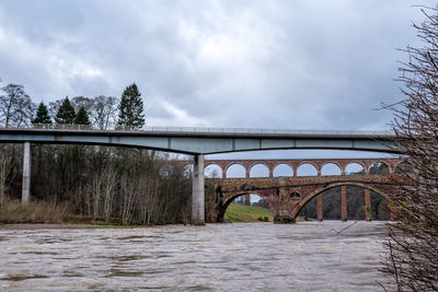 Arch bridge over river against sky