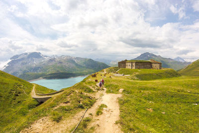 People walking on road by mountains against sky
