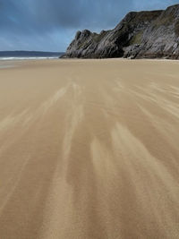 Sand dune on beach against sky