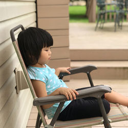 Side view of girl sitting on chair