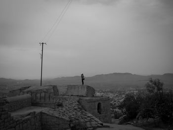 Man standing on old ruin against sky