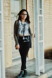 Portrait of smiling young woman standing against wall