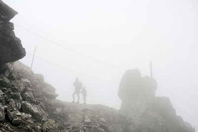 People on rock against sky