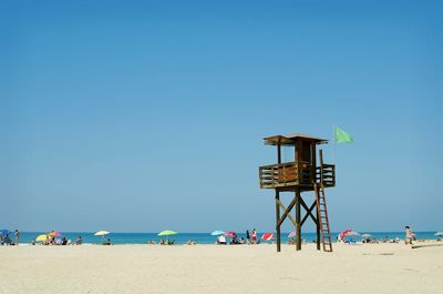 Lifeguard hut on beach against clear blue sky