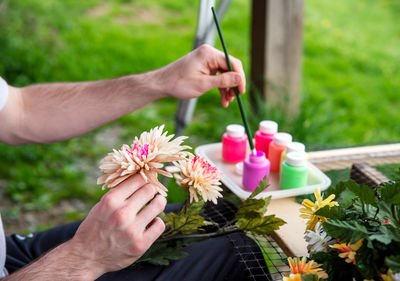 Closeup of a male artist's hands painting silk flowers outdoors art therapy creativity concept