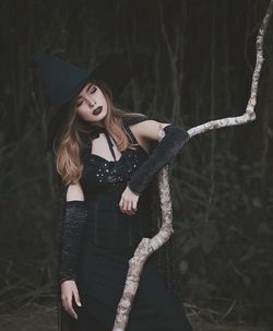 Woman in witch costume standing by tree
