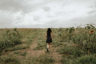 Full length rear view of young woman walking on field