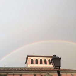 Low angle view of rainbow over building against sky