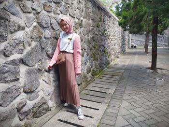 Portrait of woman standing on footpath