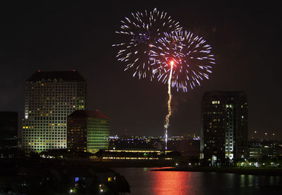 Firework display over illuminated buildings in city at night