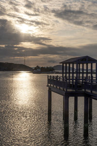 Pier on sea against sky at sunset