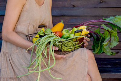 Eco-friendly concept with organic farm vegetables in the hands of a girl in a linen dress