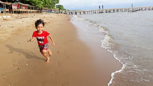 Full length of cheerful boy running at beach