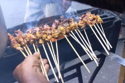 Cropped image of person preparing food on barbecue grill