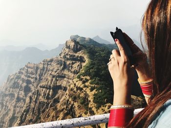 Close-up of woman photographing mountains with smart phone