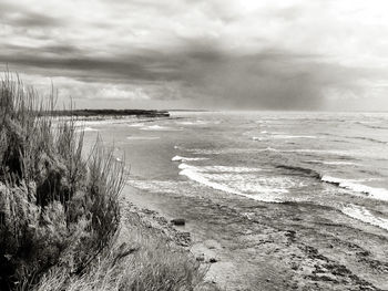 Scenic view of beach against cloudy sky