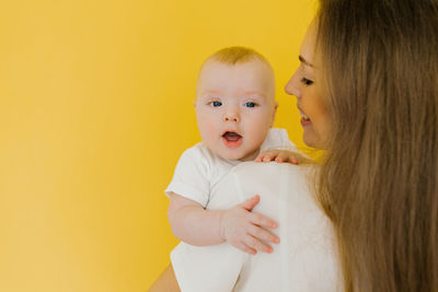 Happy mother holds her baby in her arms. a young beautiful mother holds her baby son and hugs him