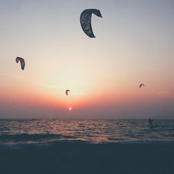 Man kiteboarding in sea against sky during sunset