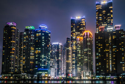 Illuminated buildings in city against sky at night