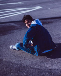 Side view of man sitting on road