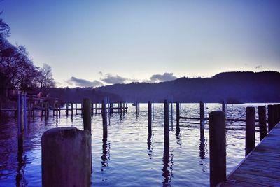 Wooden posts in lake against clear sky