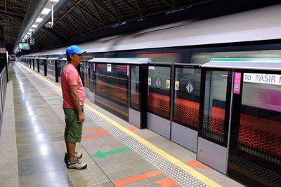 Side view of man standing at railroad station