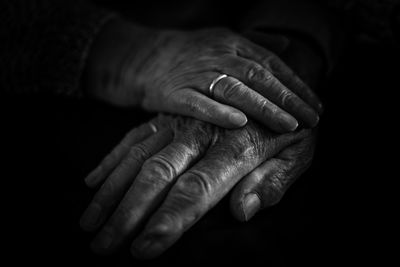 Cropped hands of senior couple against black background