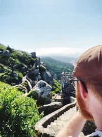 Portrait of young man looking at mountain against sky