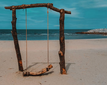 Wooden posts on beach against sky