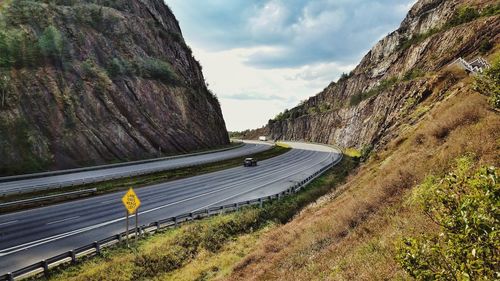 Road by mountains against sky