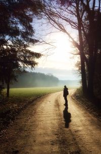 Silhouette man walking on road against sky