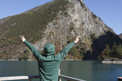 Rear view of person standing at observation point against mountain