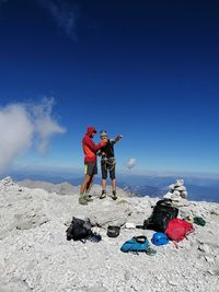 Men standing on rock against blue sky