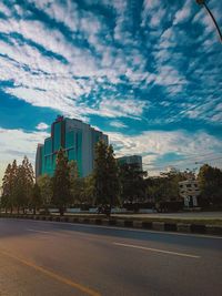 Road by buildings against sky in city