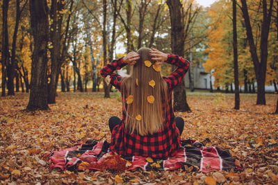 Woman standing with leaves on field during autumn